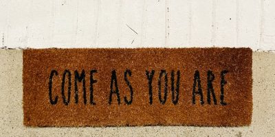 person standing on brown and black welcome printed floor mat
